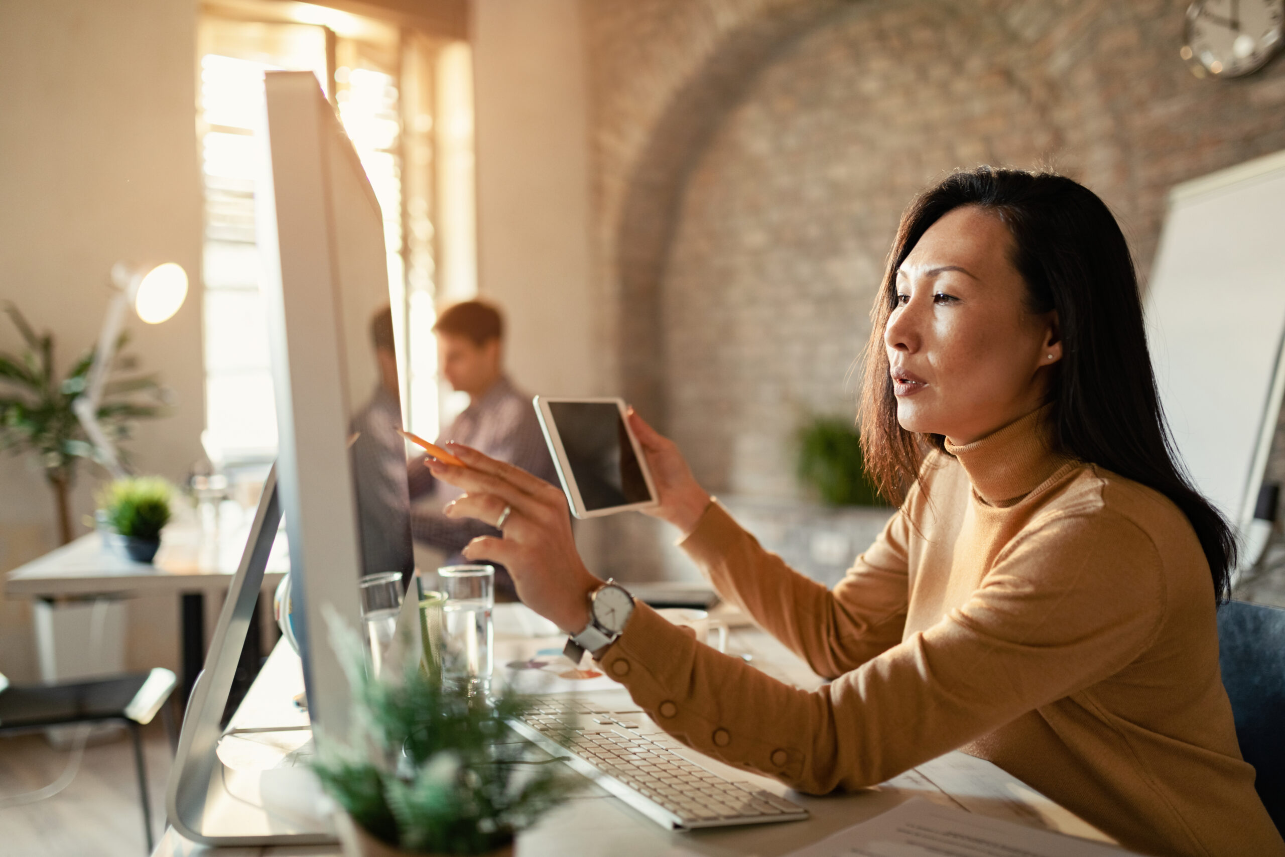 Asian female entrepreneur examining business progress on computer monitor in the office.