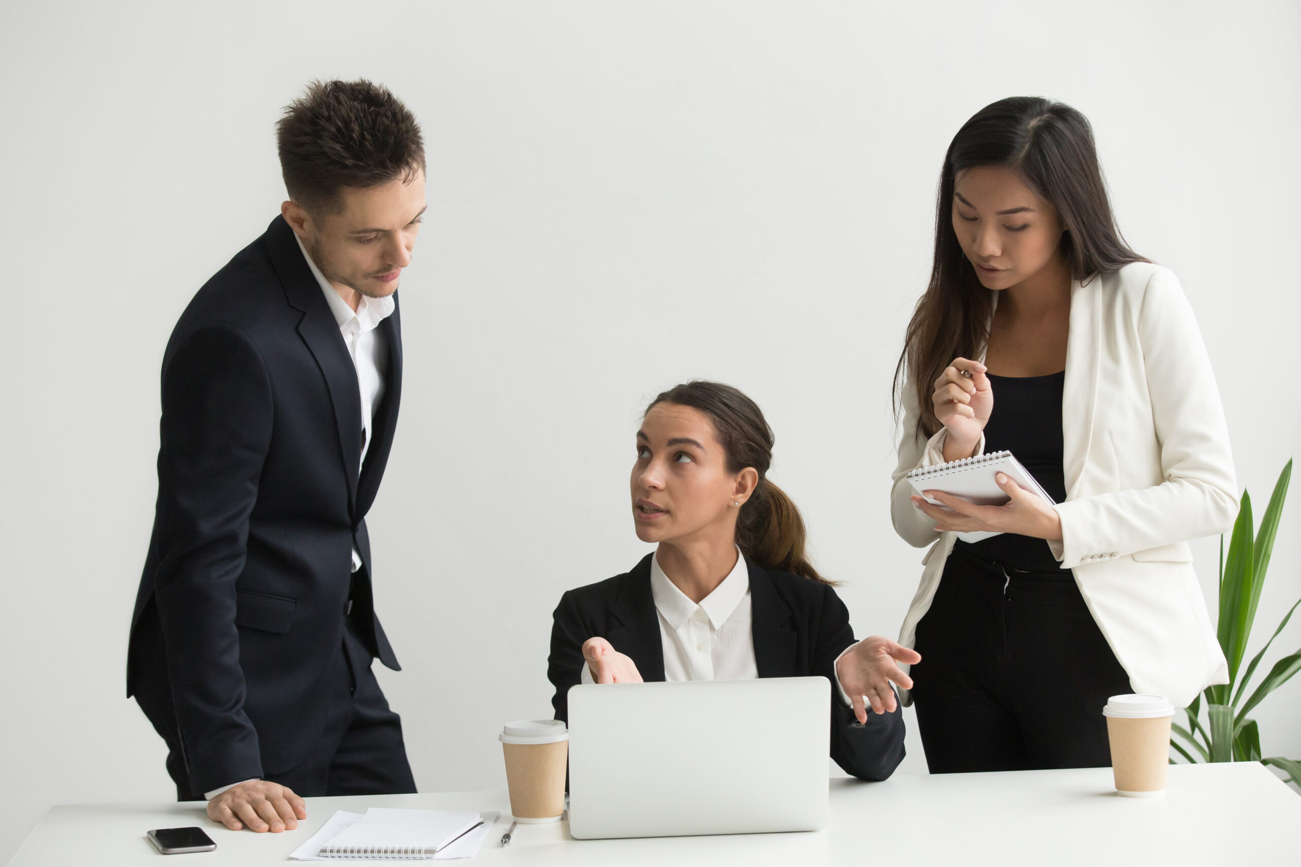 Company female CEO talking to subordinates, asking to explain bad statistics and results. Team leader training colleagues, presenting information on laptop, workers listening attentively writing down.